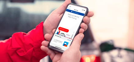hand holding Iphone with ExxonMobil gas rewards app open