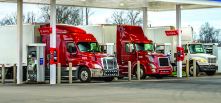 Two red trucks at ExxonMobil Synergy Diesel Efficient fuel pumps