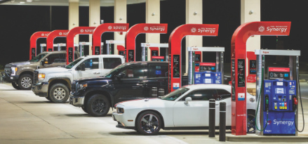 four cars at Exxon Synergy Supreme+ premium gas pumps at night