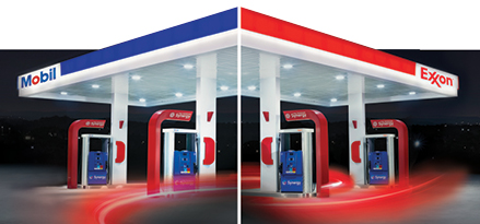 A Mobile and Exxon station with fuel pumps at night