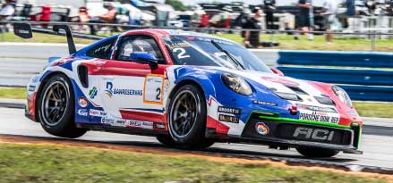 Red, white, and blue Porsche Carrera racing on a track