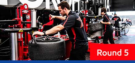 Porsche Carrera Pit crew in black and red uniforms working on tires