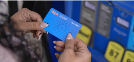 Woman holding an Exxon Mobil Smart Card+ at a gas station